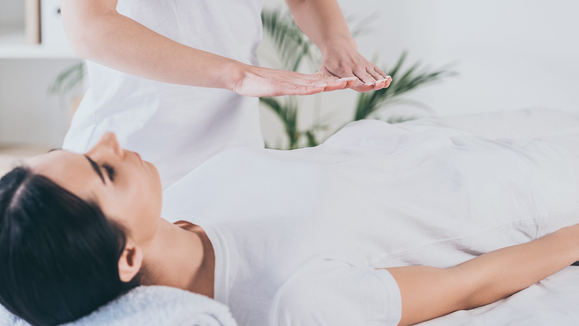 energy healing provided by a women doing reiki with hands hovering over a persons body laying on top of a table